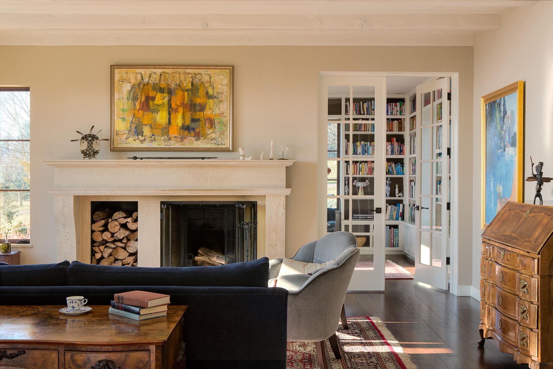 Living room with fireplace, layered textures, vintage furnishings and natural light in a refined Portland home