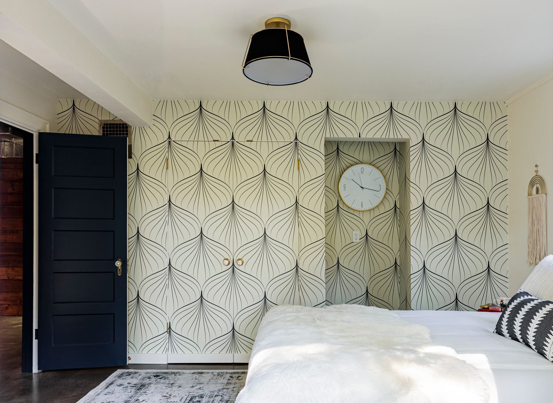 modern vintage bedroom with graphic wallpaper, black door, and neutral layered bedding