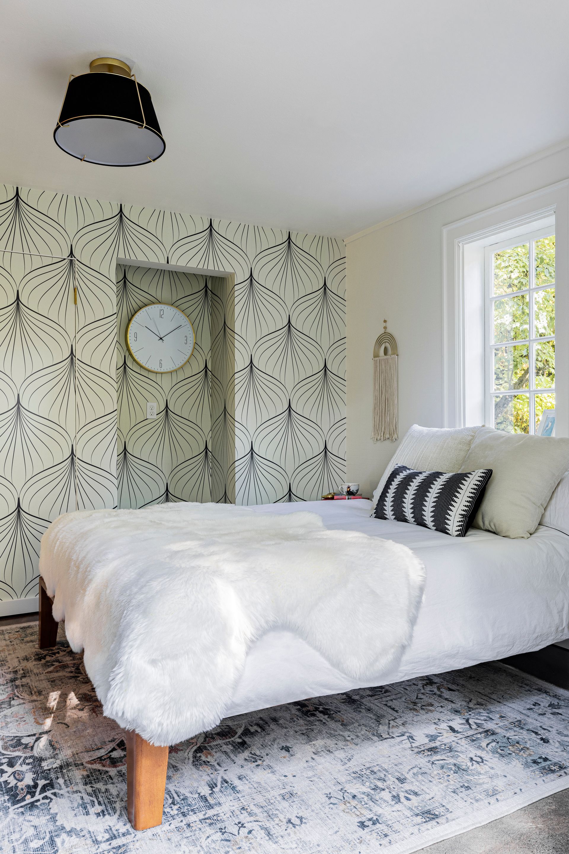 modern bedroom with graphic wallpaper, natural light, neutral bedding, and soft layered textiles
