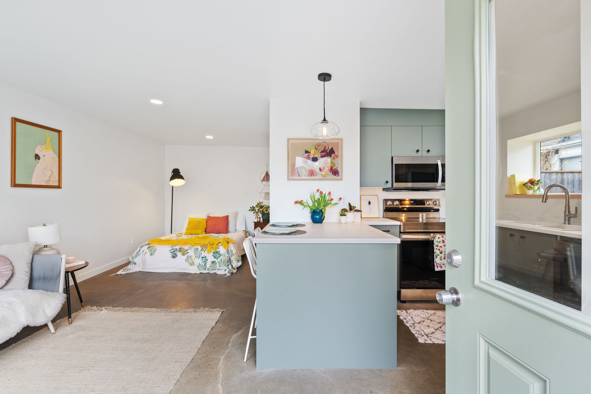 modern ADU studio design with kitchen and bedroom, green cabinets, open layout, and natural light