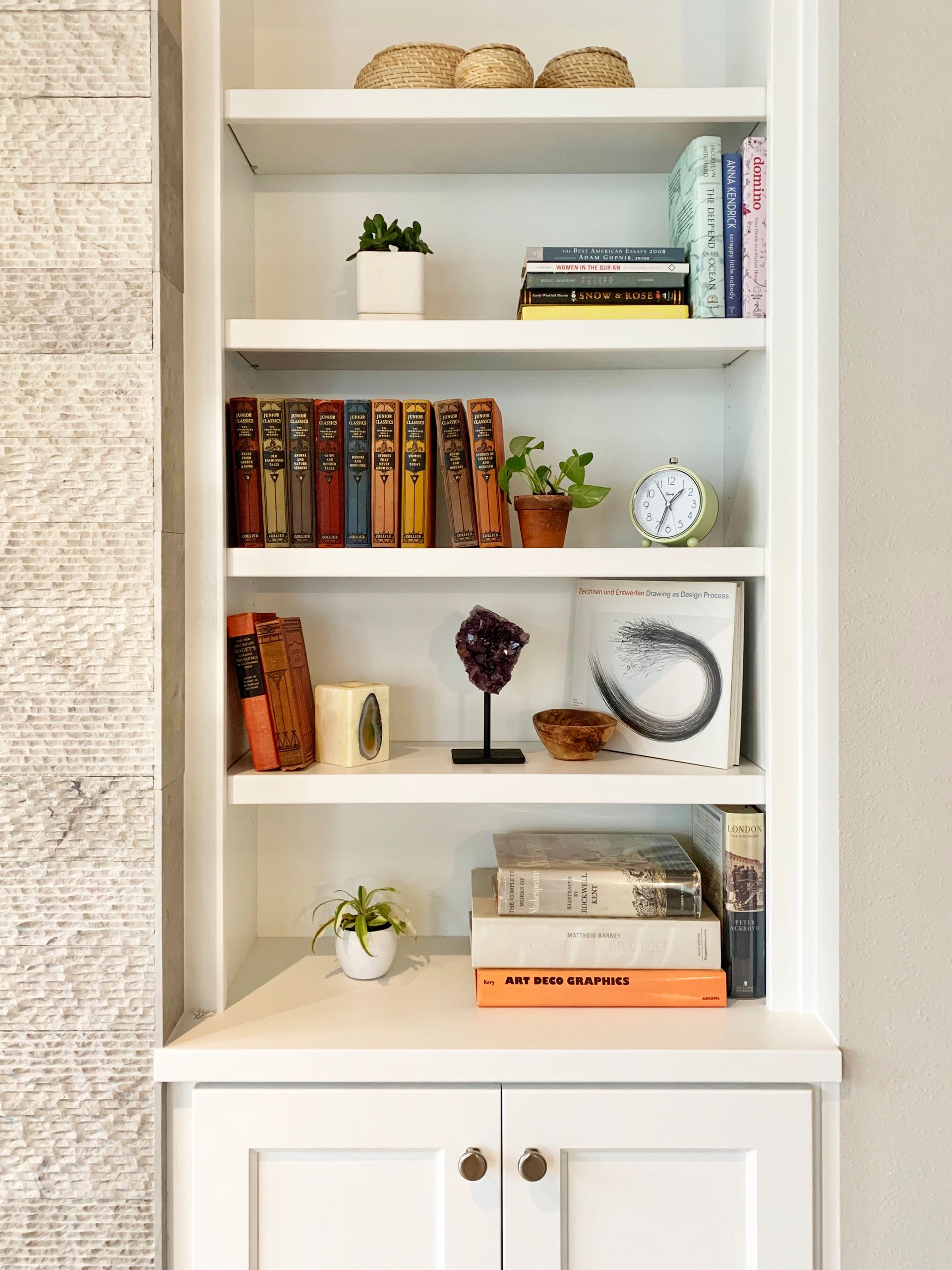 Styled interior vignette with books, ceramics, and decorative objects on marble shelf