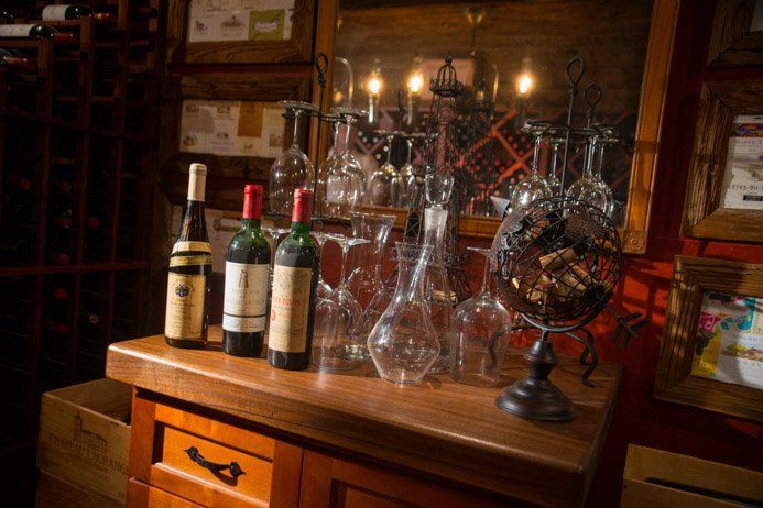 Three bottles of wine are sitting on a wooden table in a wine cellar.