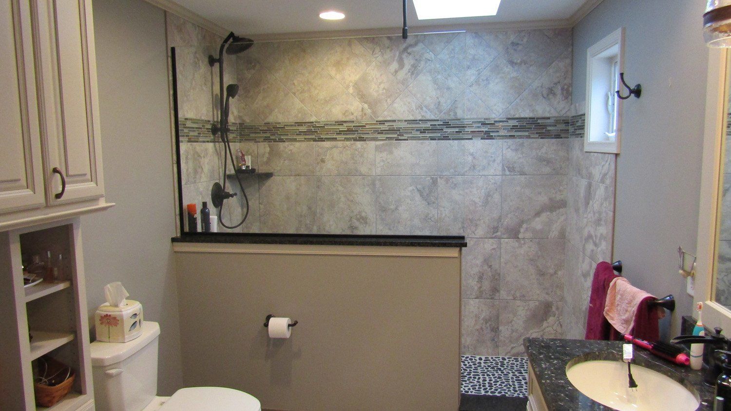 A bathroom with a toilet , sink , mirror and shower.