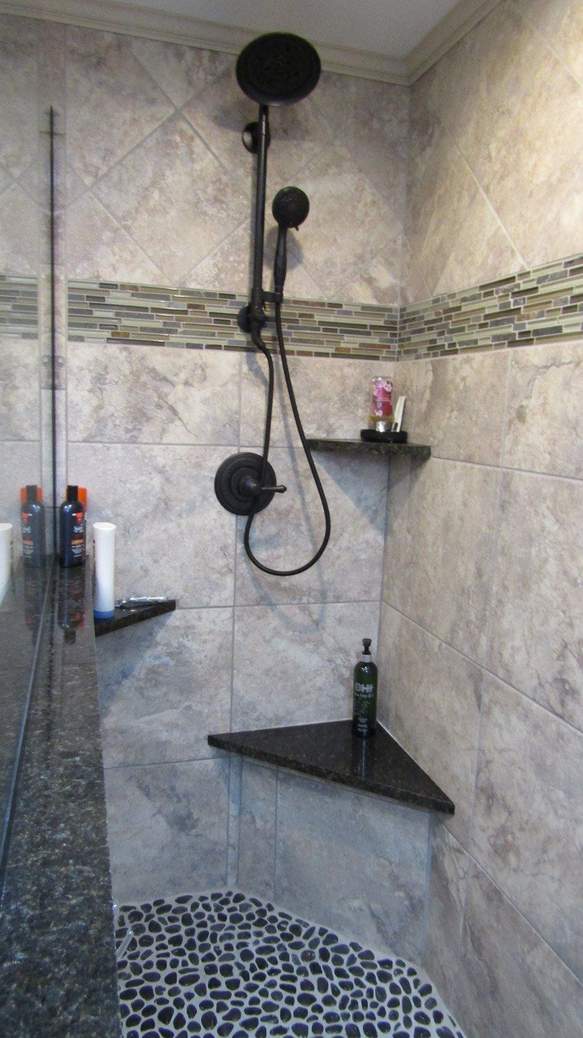A shower with a corner shelf and a shower head.