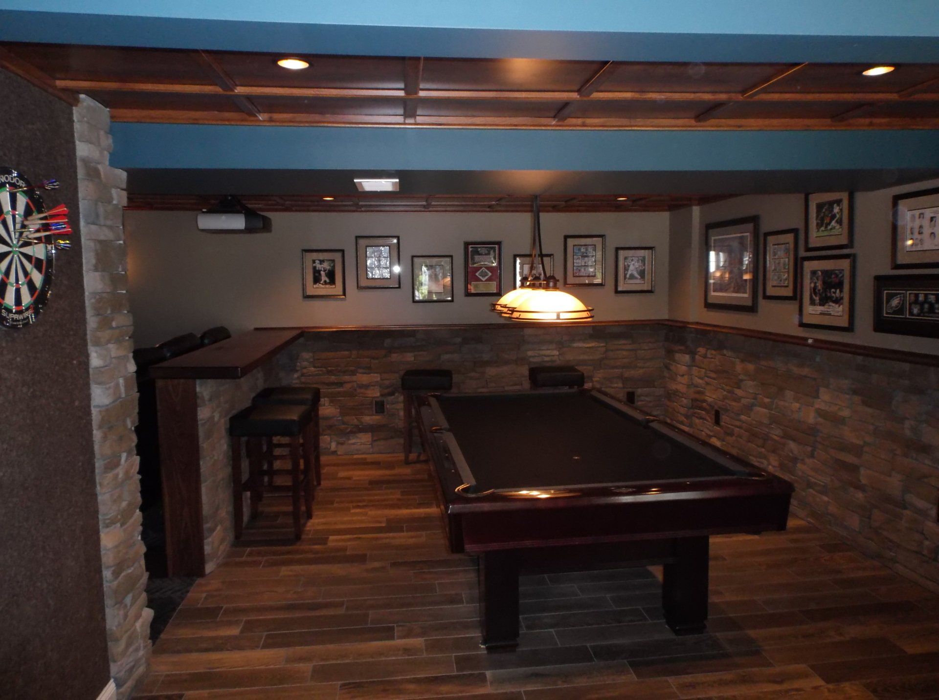 A pool table in a basement with a dart board on the wall