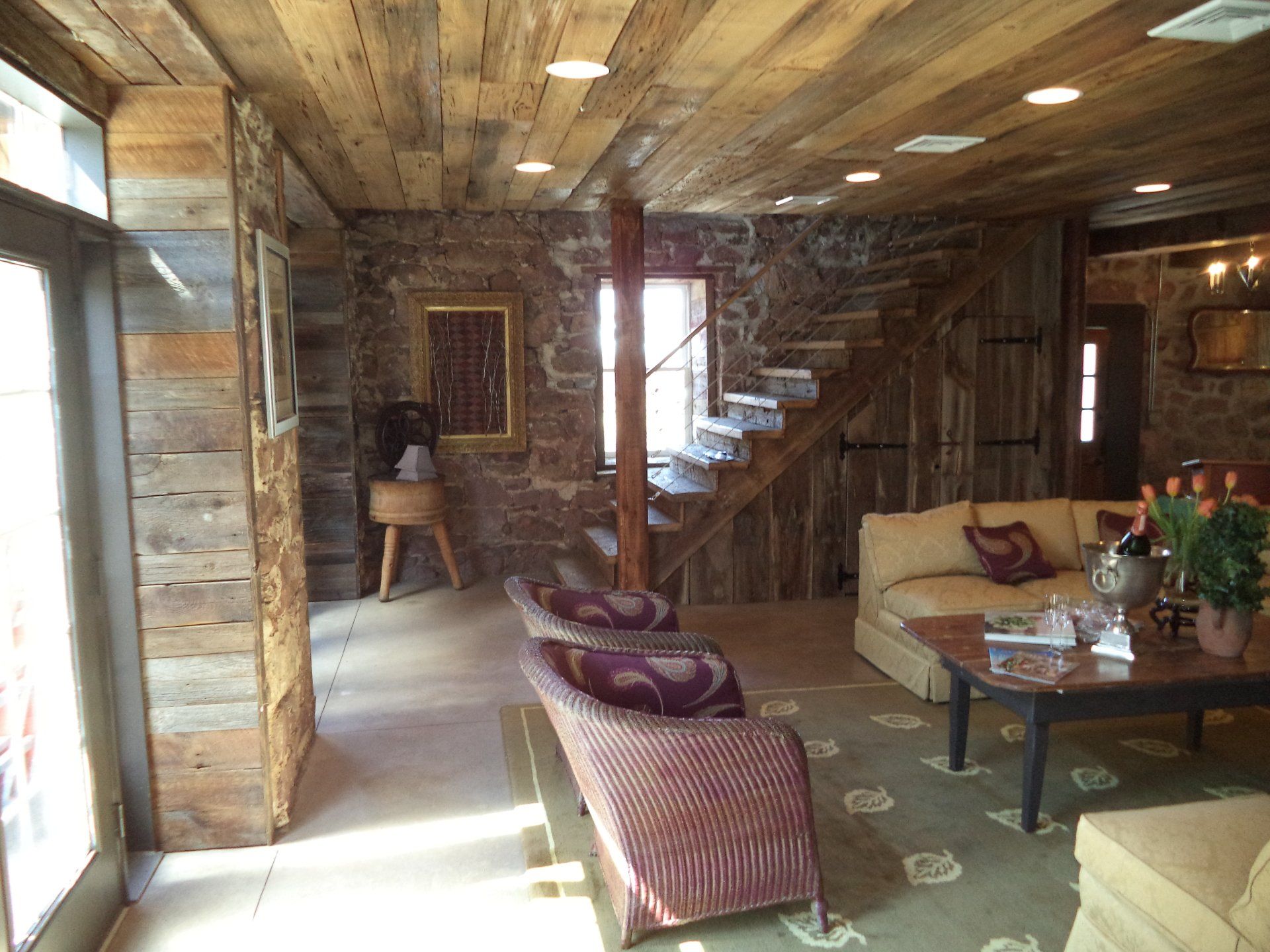 A living room with a wooden ceiling and stairs