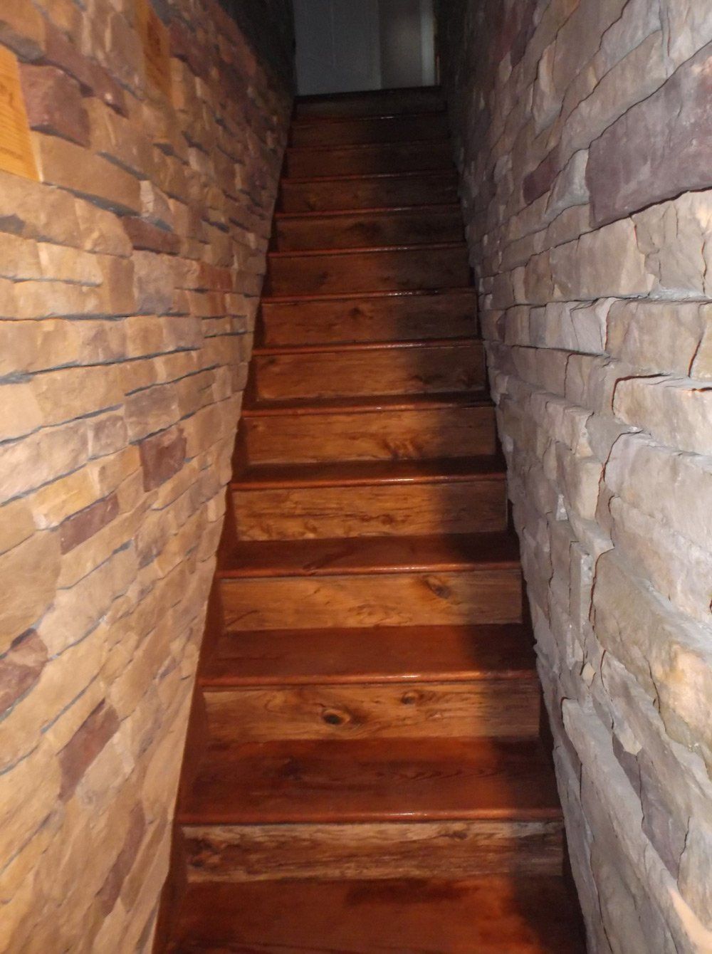 A wooden staircase leading up to a stone wall.