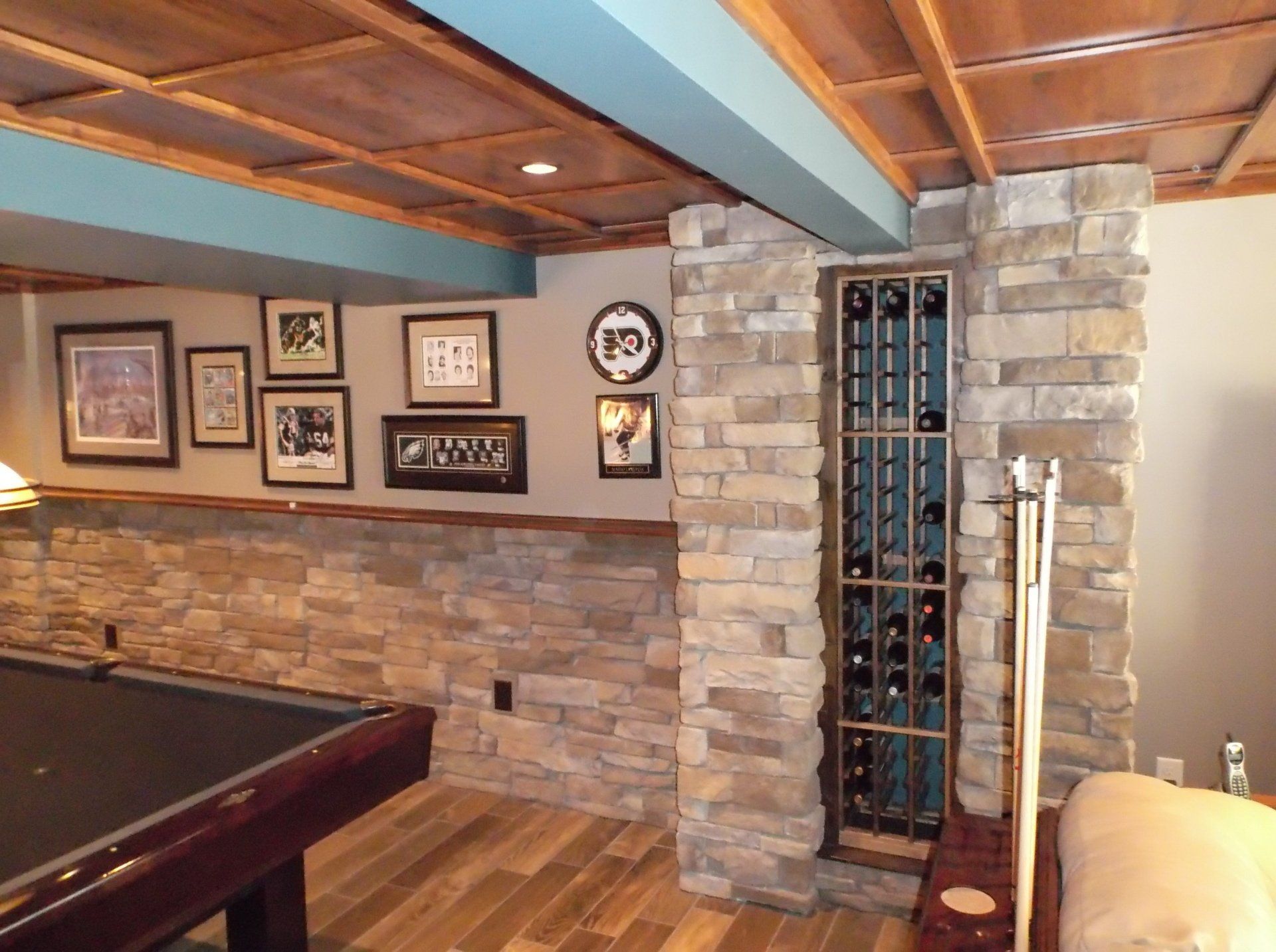 A pool table in a basement with pictures on the wall