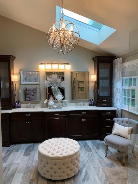 A bathroom with two sinks a chair and an ottoman