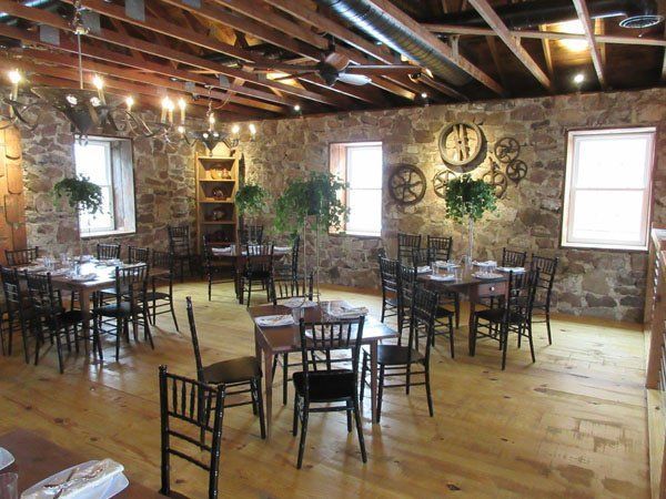 A dining room with tables and chairs and a stone wall