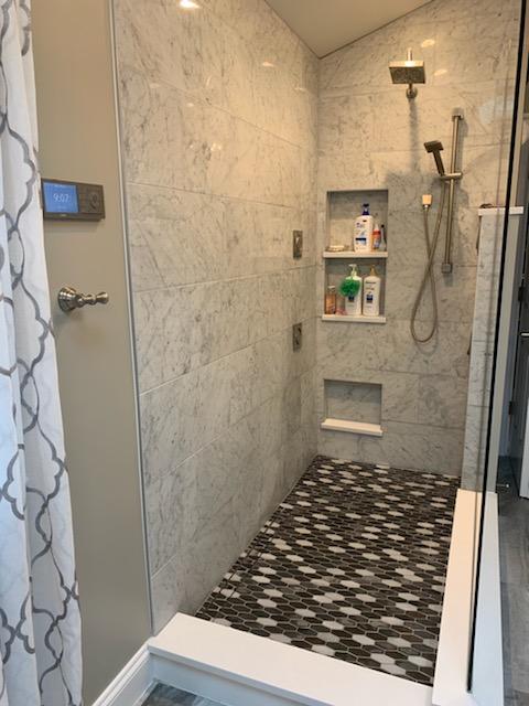 A bathroom with a walk in shower with a glass door.