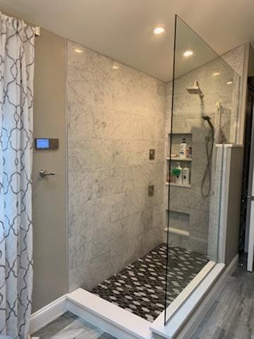 A bathroom with a walk in shower with a glass door.