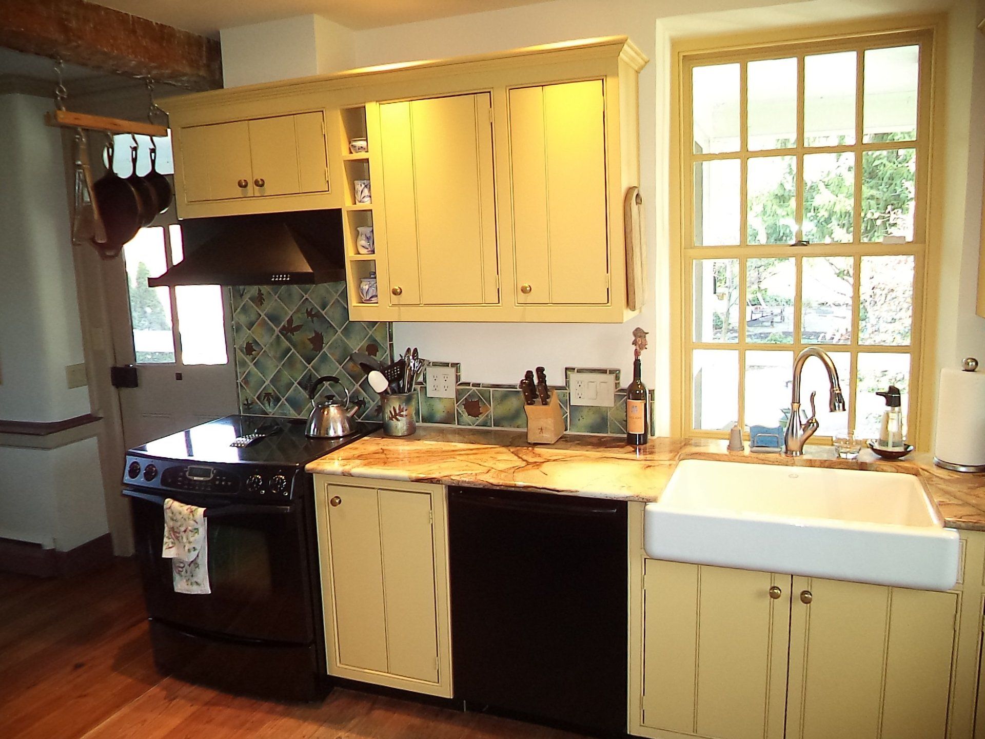 A kitchen with yellow cabinets and black appliances