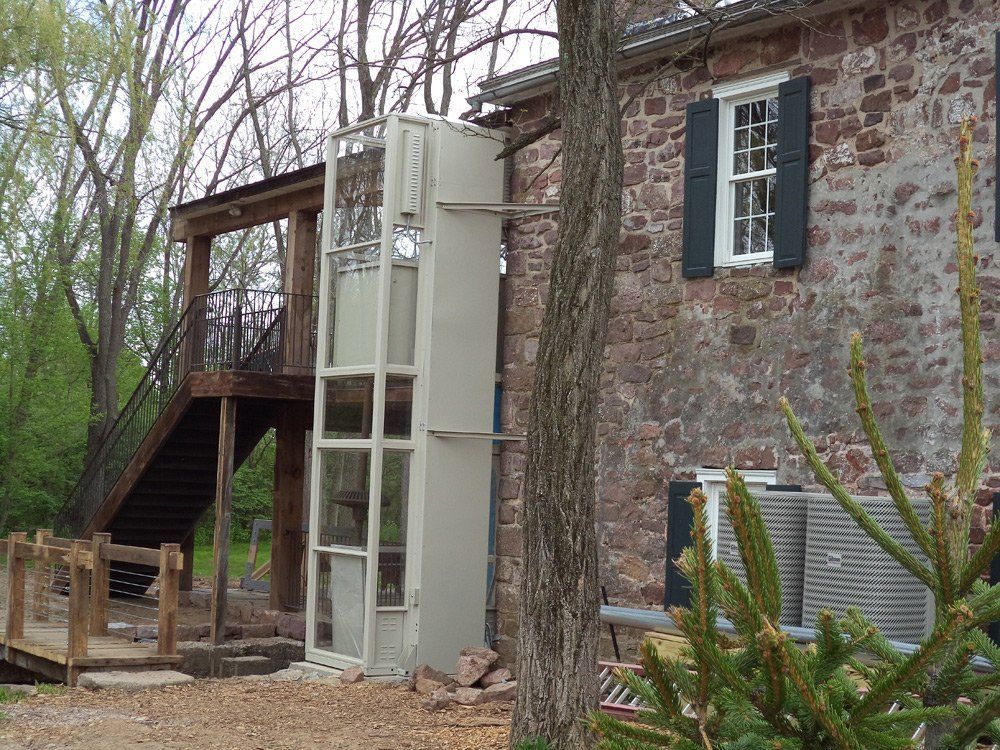 A white elevator is attached to the side of a brick building.