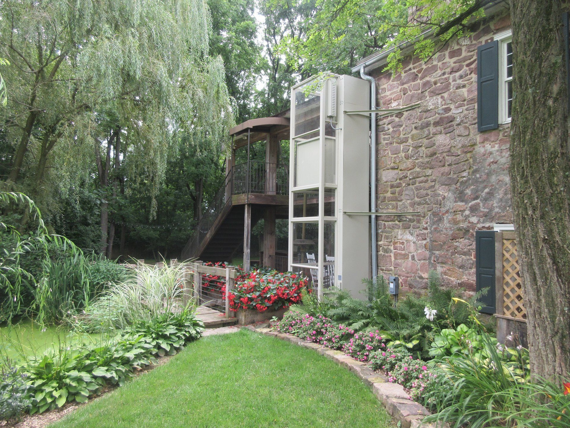 A brick house with a staircase and a lawn in front of it