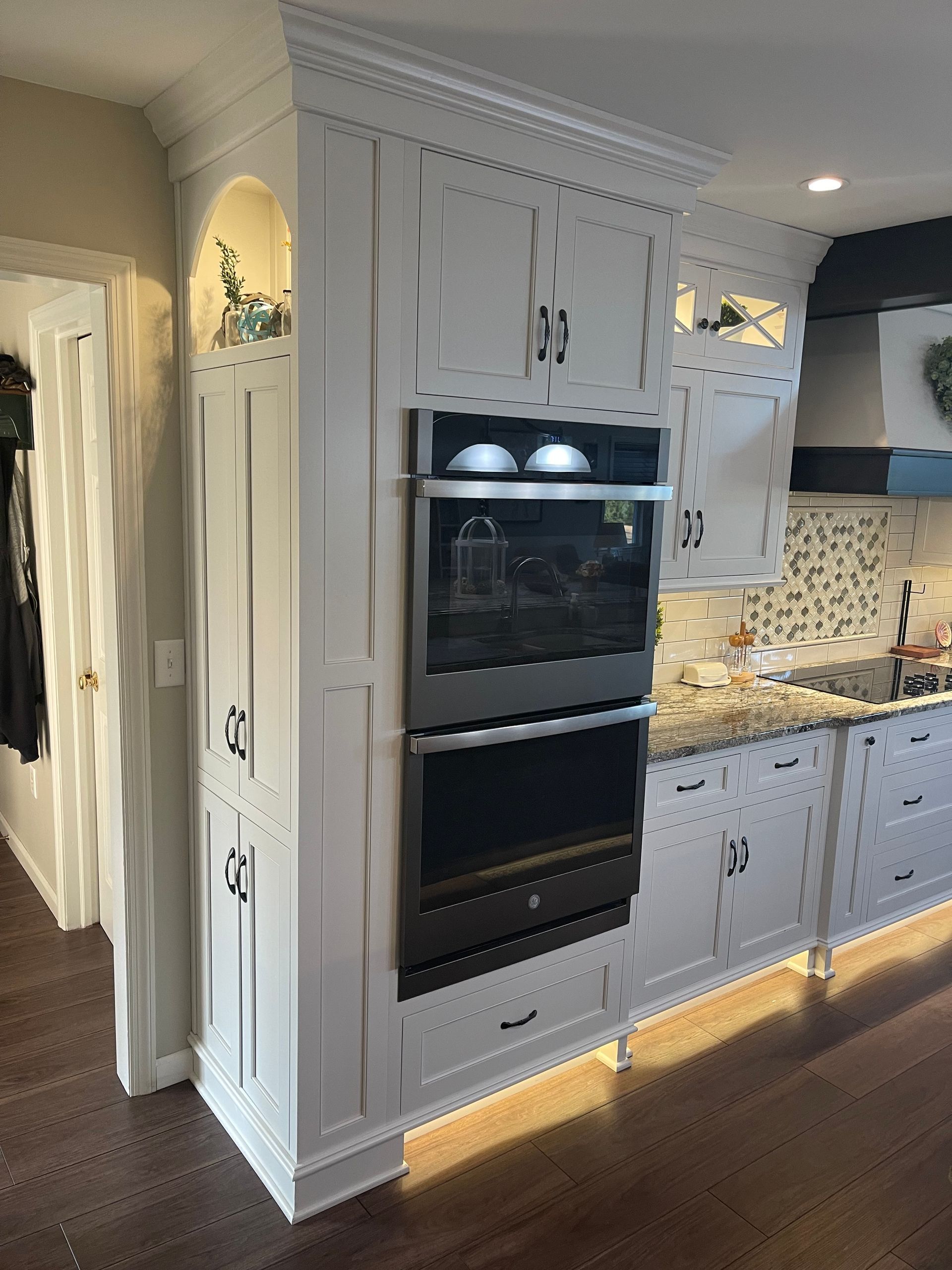 A kitchen with white cabinets and a black oven.