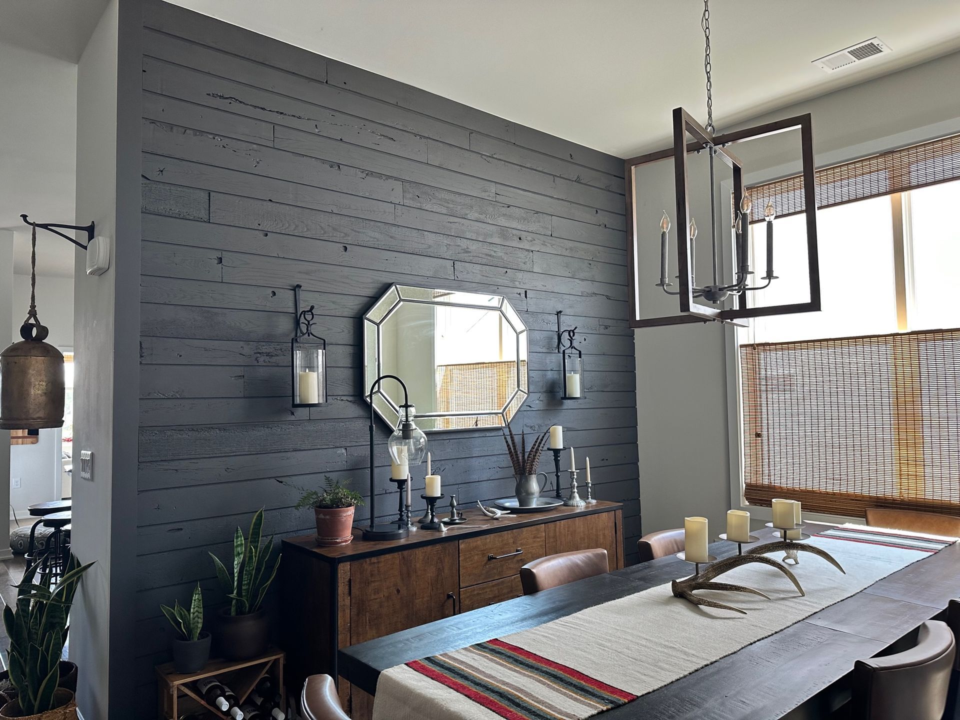 A dining room with a table and chairs and a mirror on the wall.