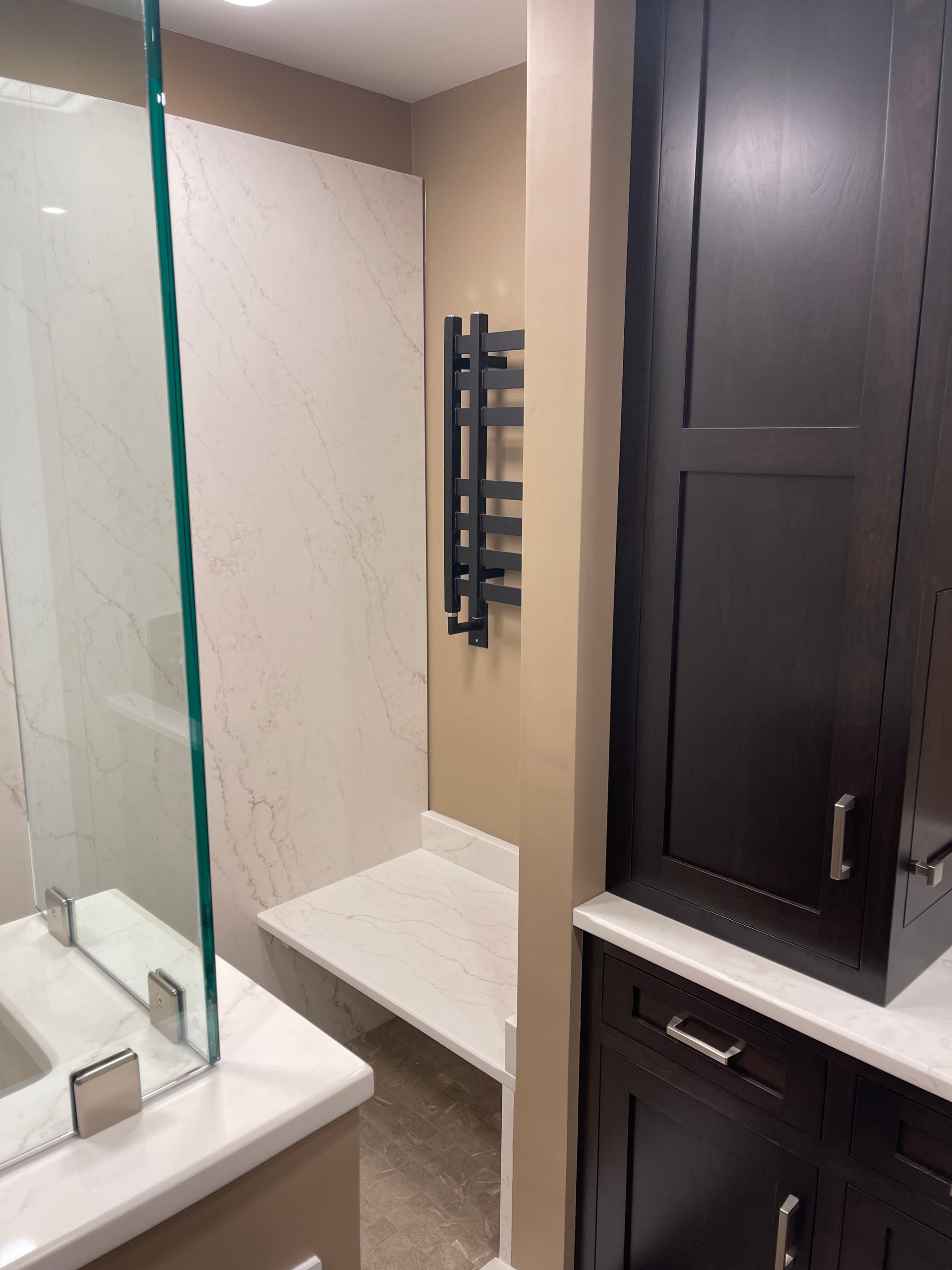 A bathroom with a glass shower door and a bench.