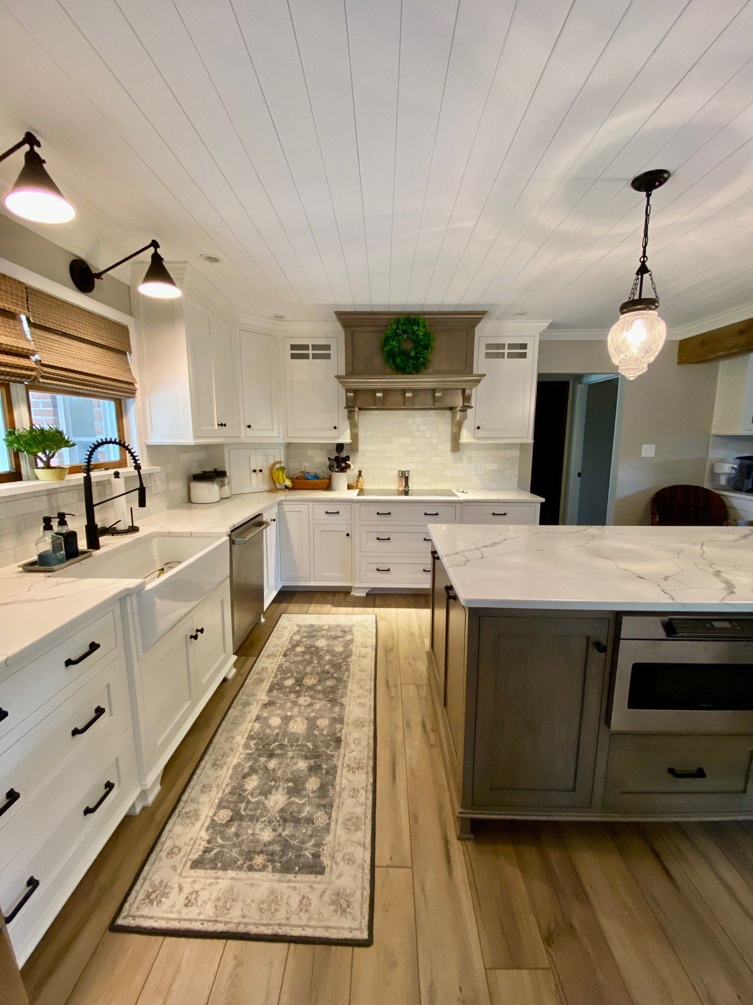 A kitchen with white cabinets , stainless steel appliances , and a large island.