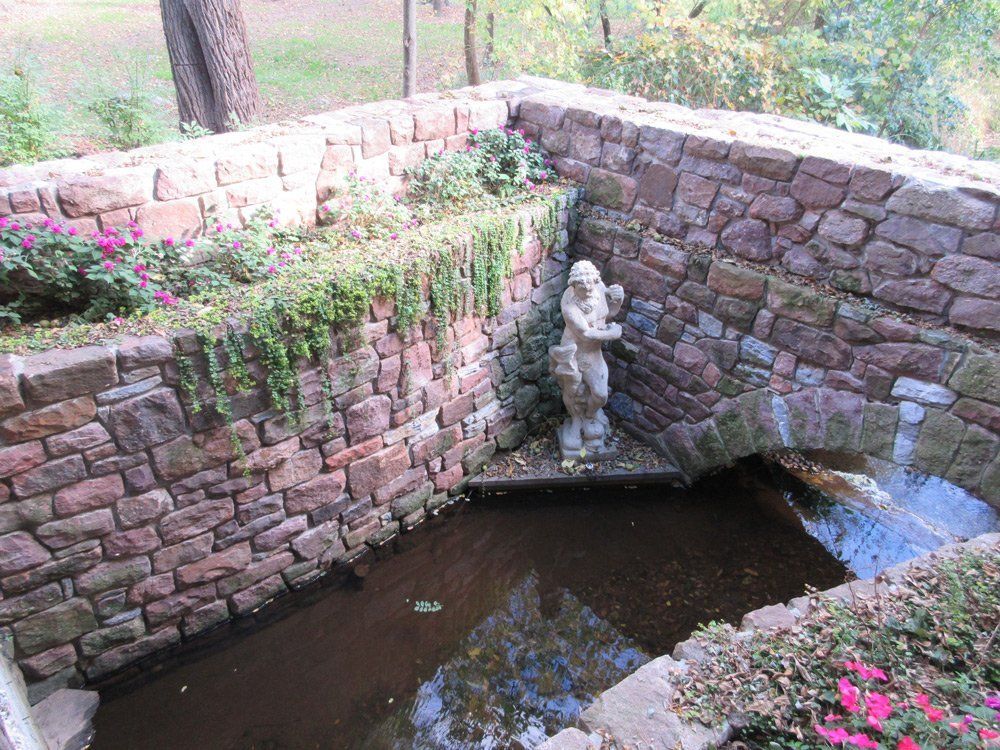 A stone bridge over a pond with a statue in the middle.