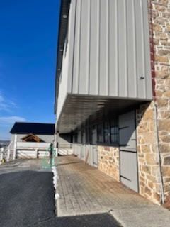 A large building with a stone wall and a metal roof.
