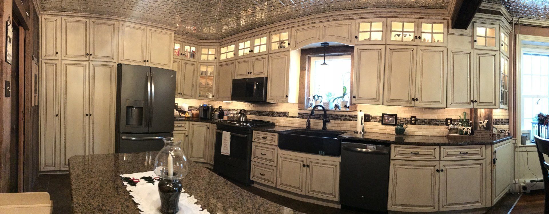 A kitchen with white cabinets , black appliances and granite counter tops.