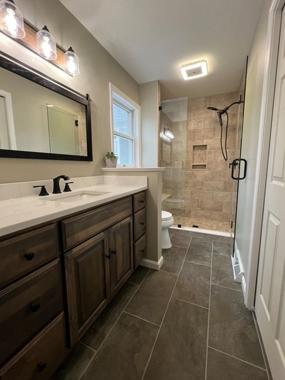 A bathroom with two sinks , a toilet , and a walk in shower.