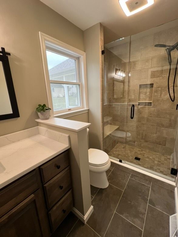 A bathroom with a toilet , sink and shower.
