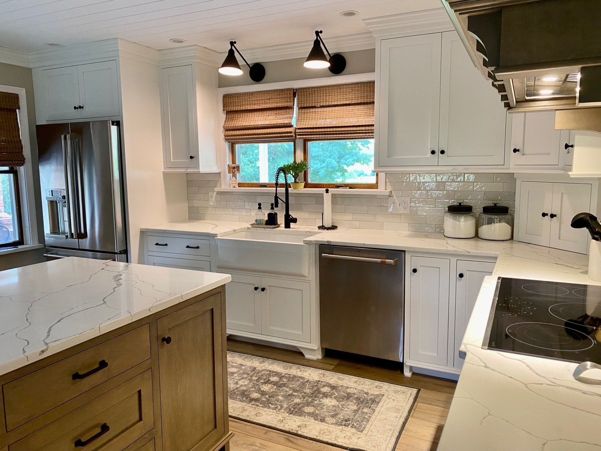 A kitchen with white cabinets , stainless steel appliances , and a large island.