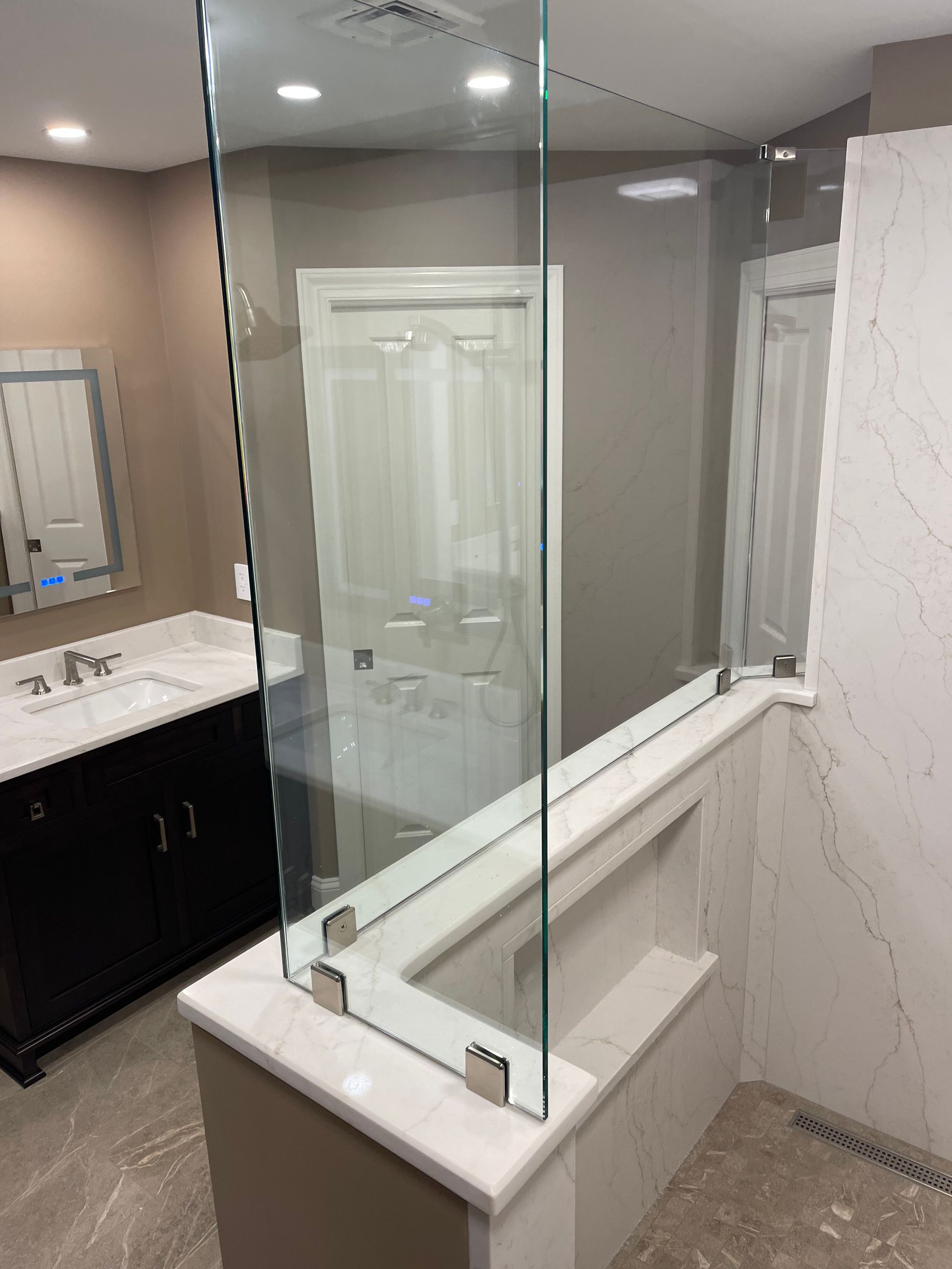 A bathroom with a glass shower door and a sink.