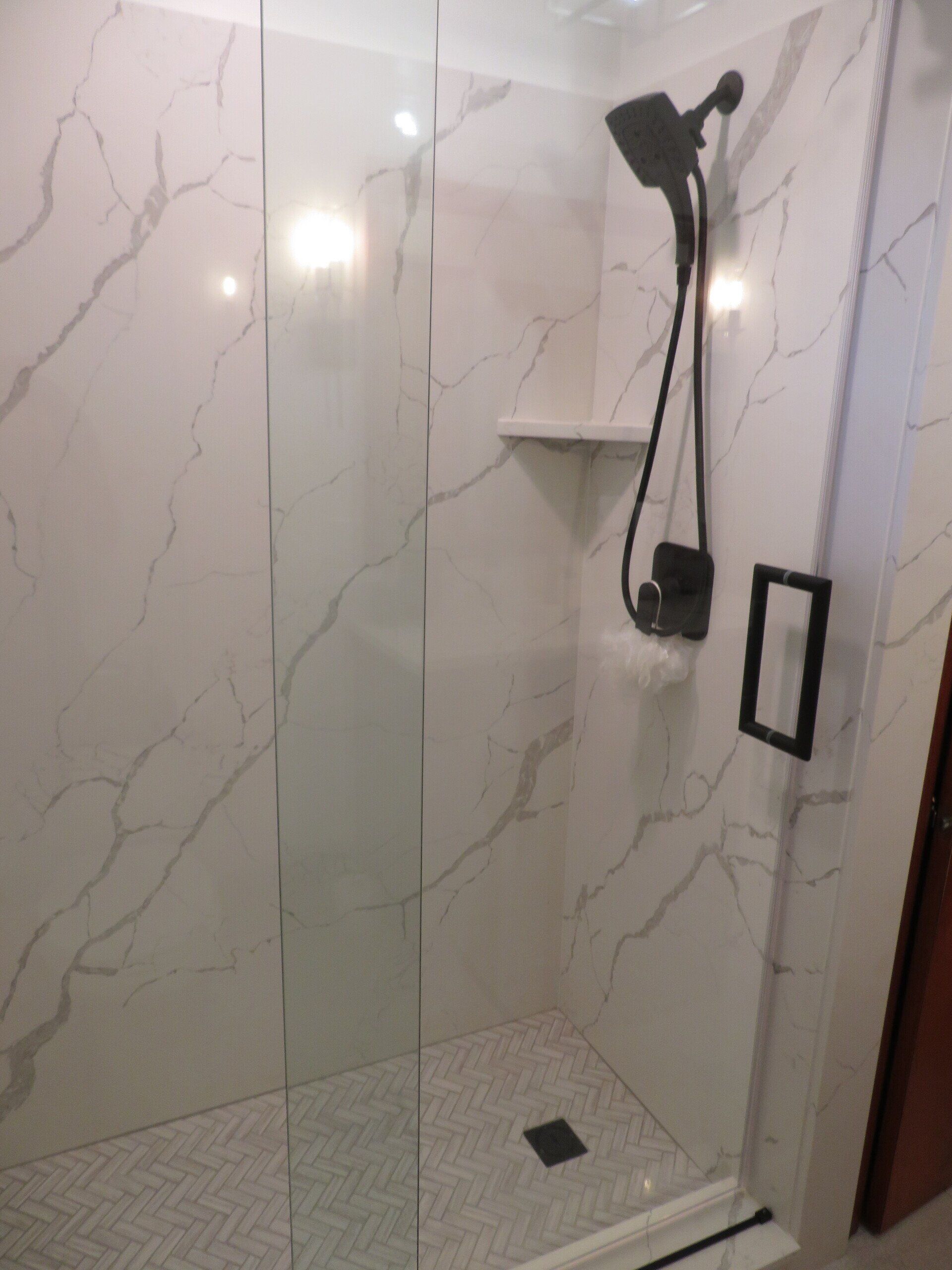 A shower with a glass door and a shower head.