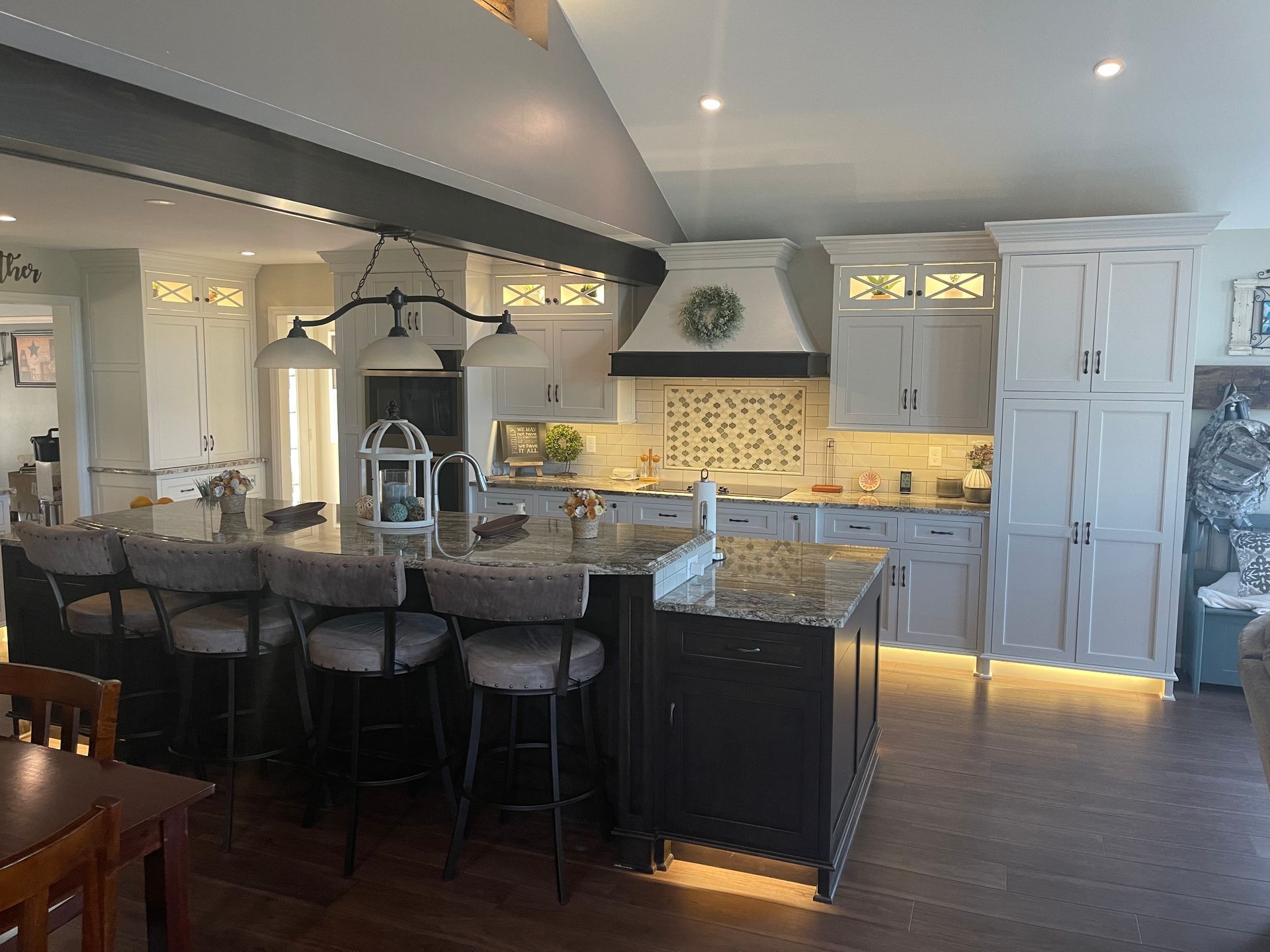 A kitchen with white cabinets , granite counter tops , and a large island.