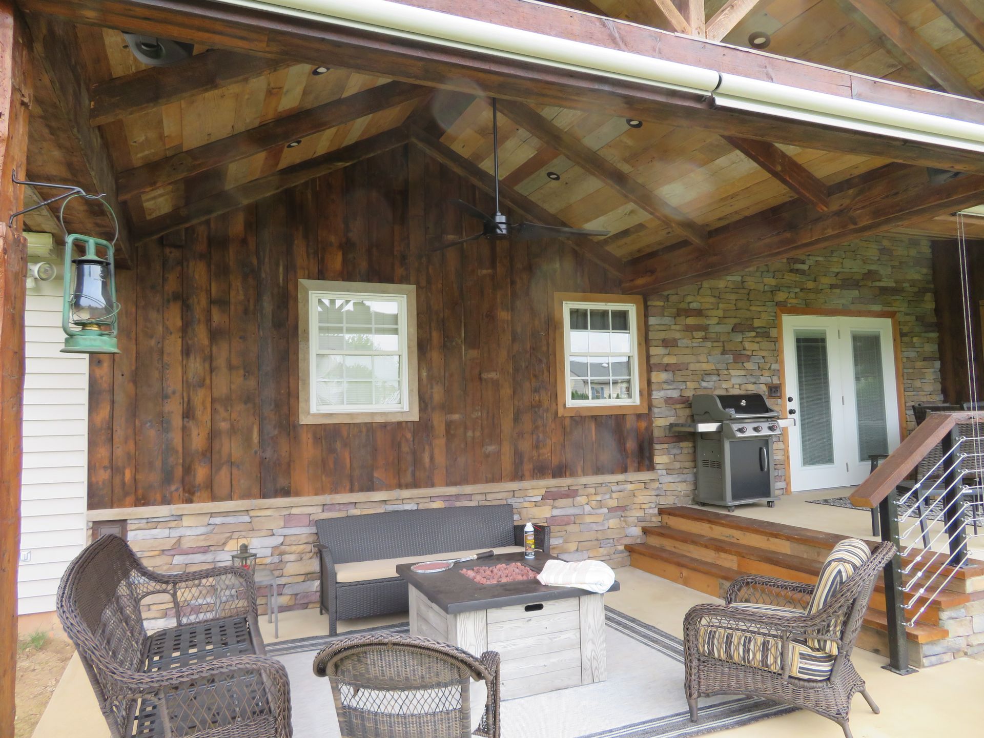 A porch with a couch , chairs , a table and a grill.