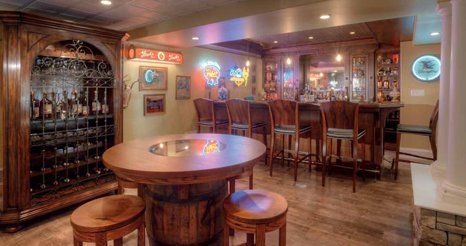 A basement bar with a table and stools and a wine cellar.