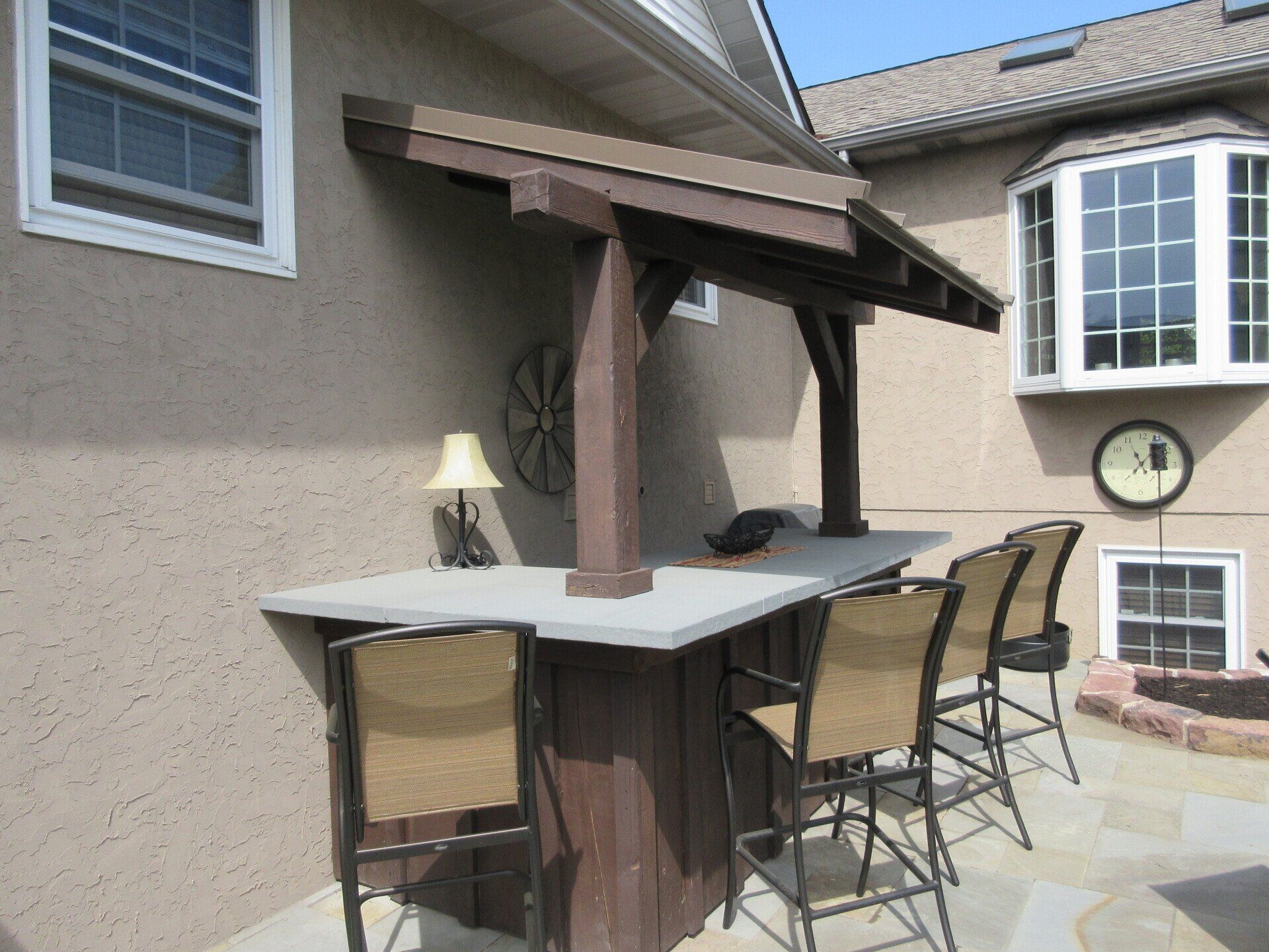 A patio with a table and chairs and a clock on the wall