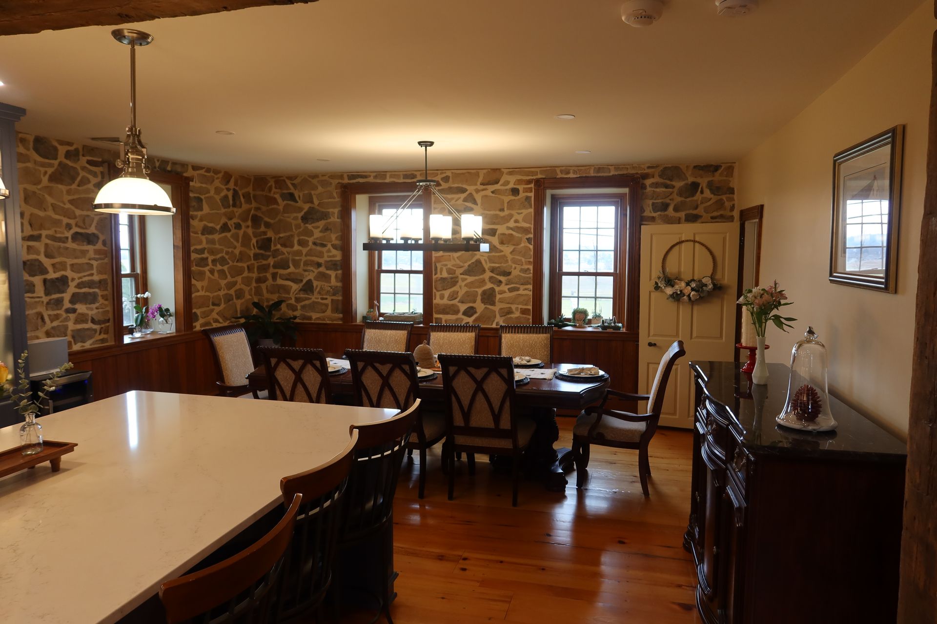 A dining room with a table and chairs and a stone wall