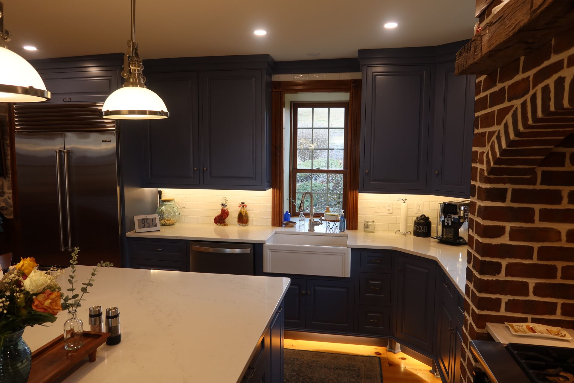 A kitchen with blue cabinets and a brick fireplace