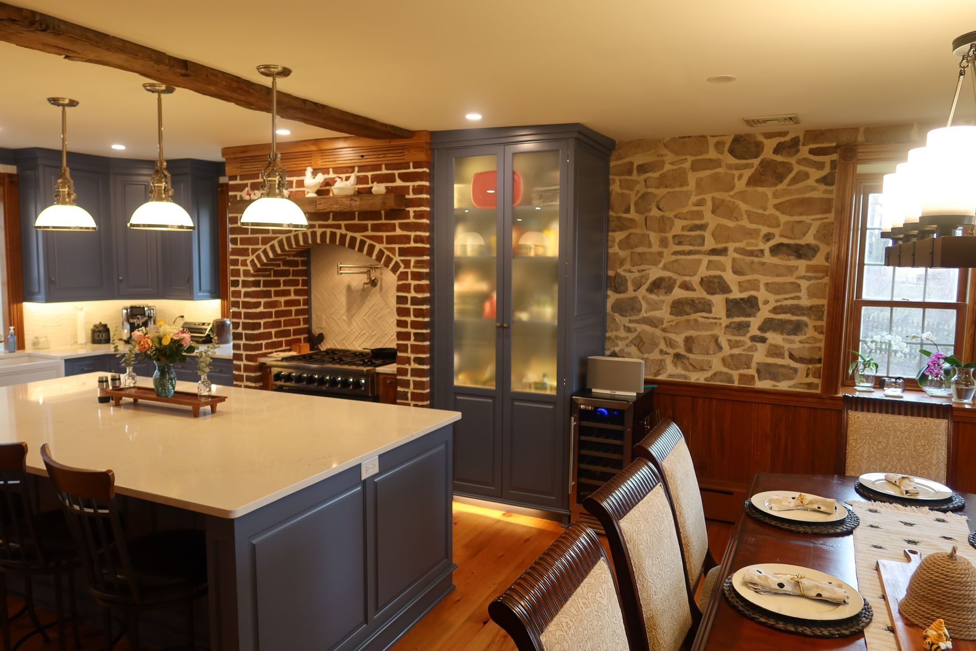 A kitchen and dining room in a house with a stone wall.