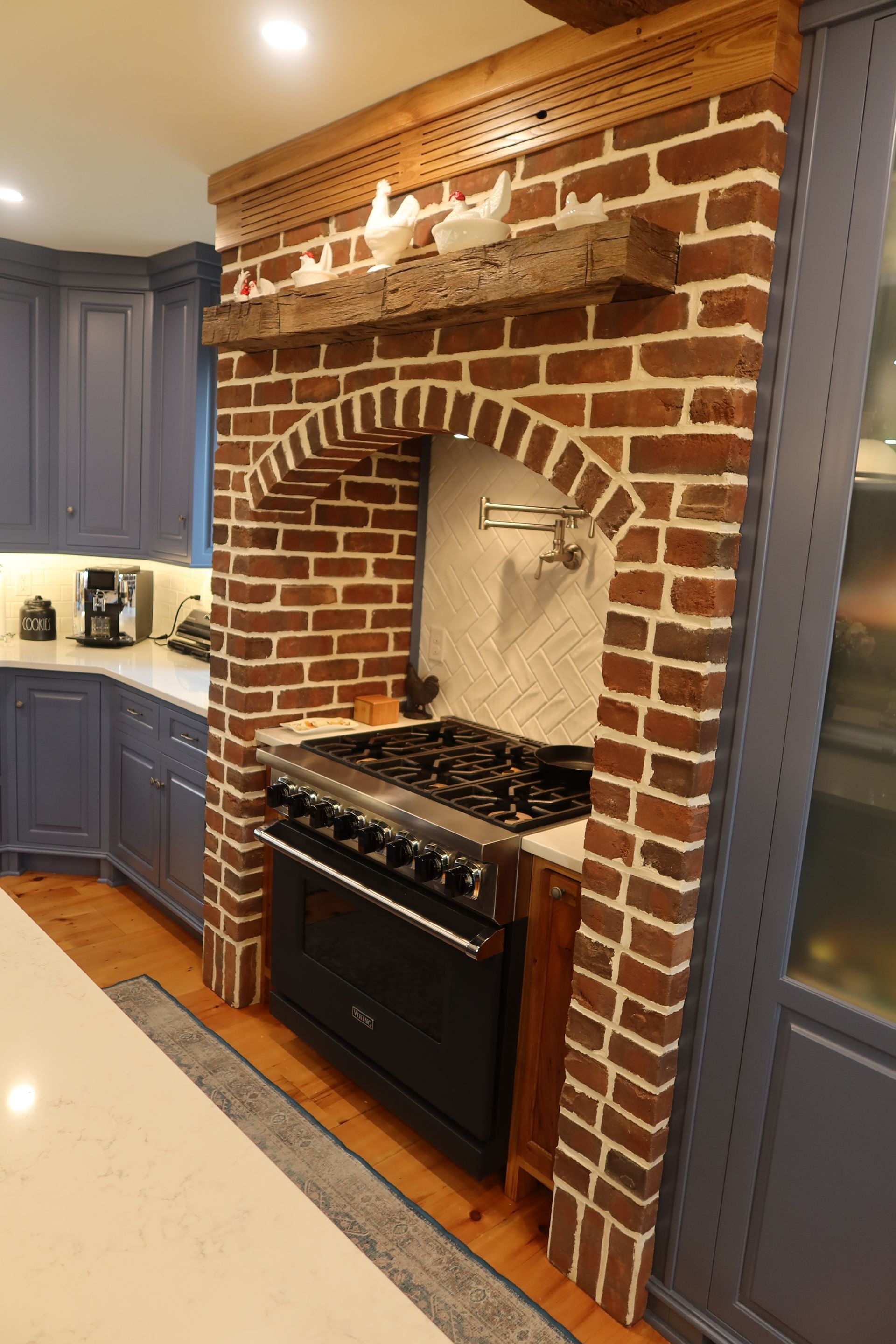 A kitchen with a stove and a brick fireplace