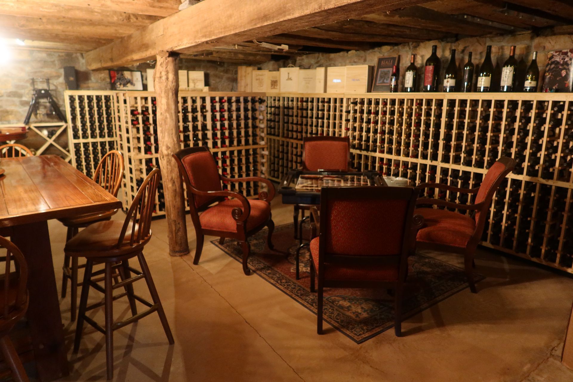 A wine cellar filled with lots of wine bottles and a table and chairs.