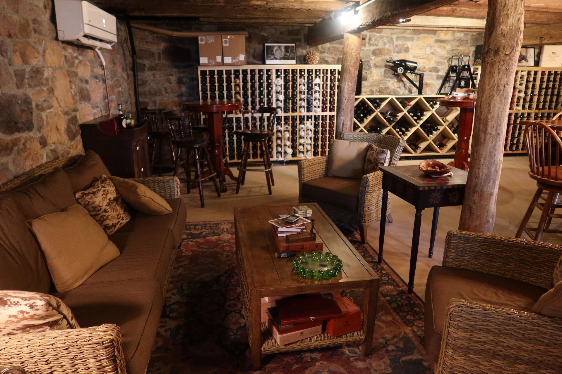 A living room with a couch , chairs and a table in a wine cellar.