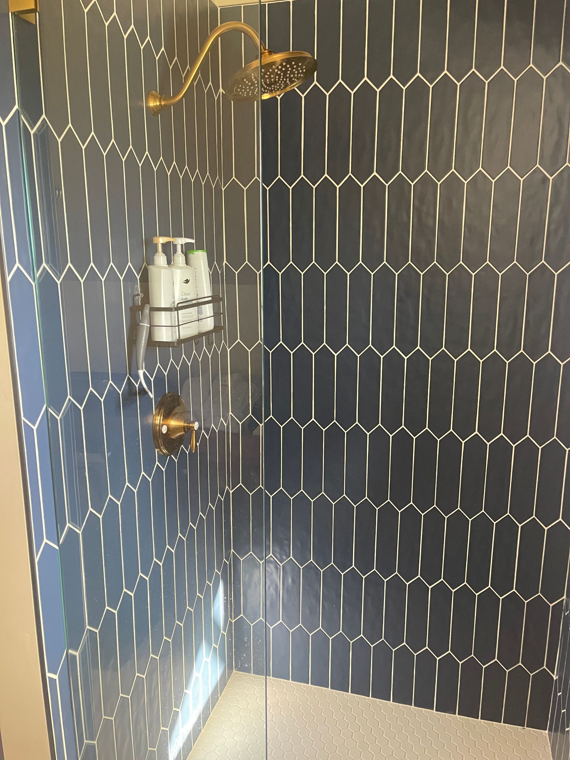 A shower with blue tiles and a glass door.