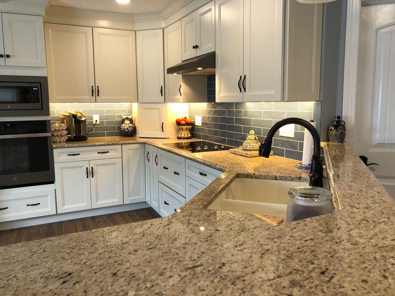 A kitchen with white cabinets , granite counter tops , and a sink.