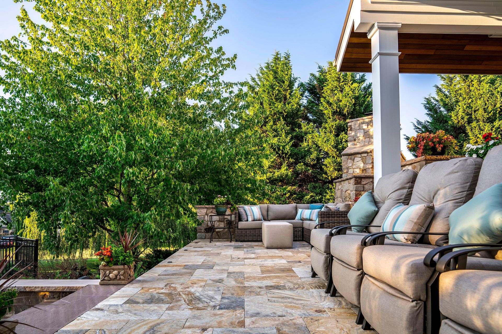 A patio with a lot of furniture and trees in the background.