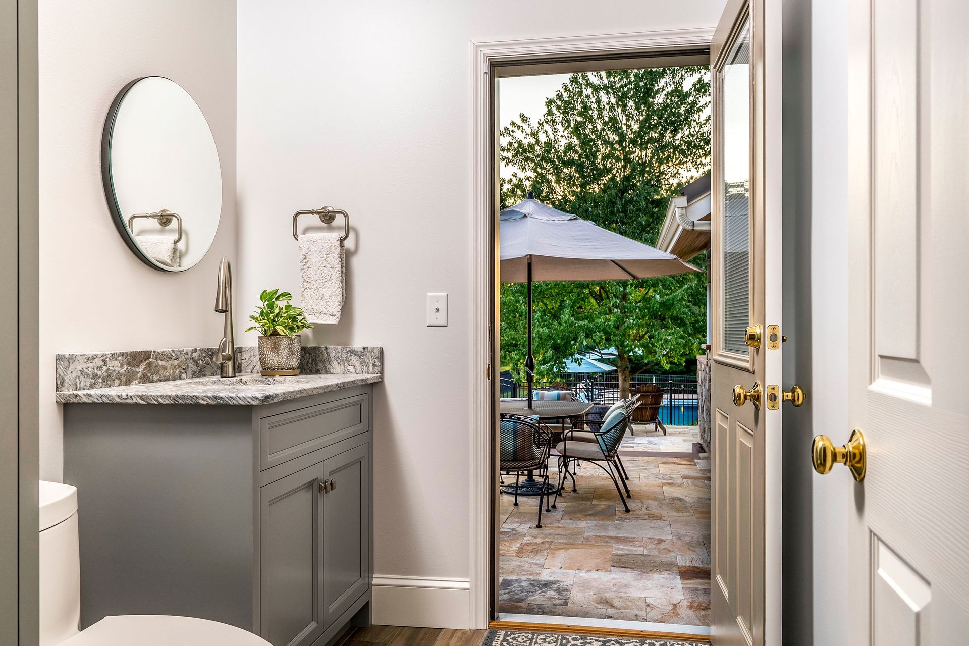 A bathroom with a sink , toilet , mirror and door leading to a patio.