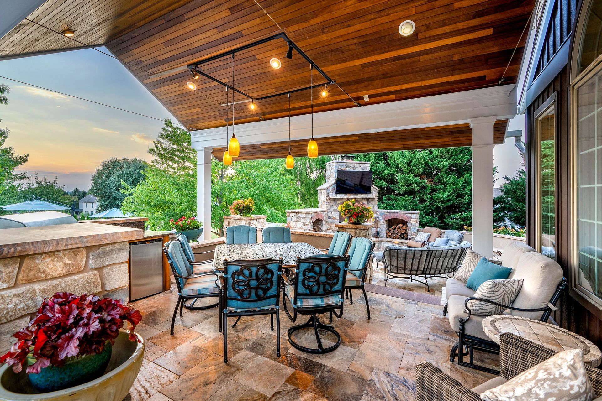 A large covered patio with a table and chairs and a fireplace.