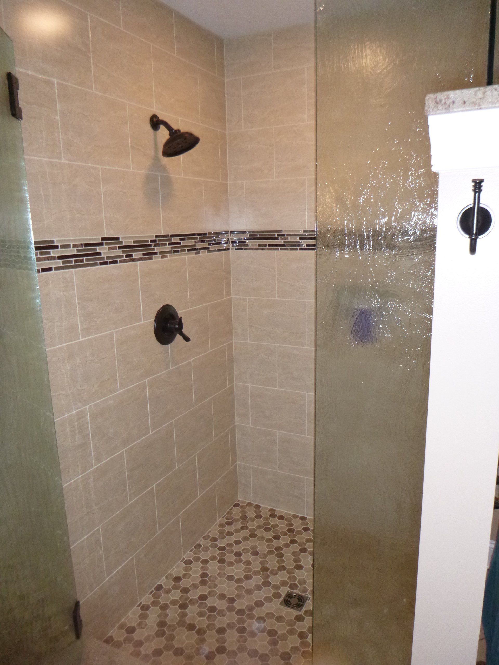 A walk in shower with a glass door and a shower head