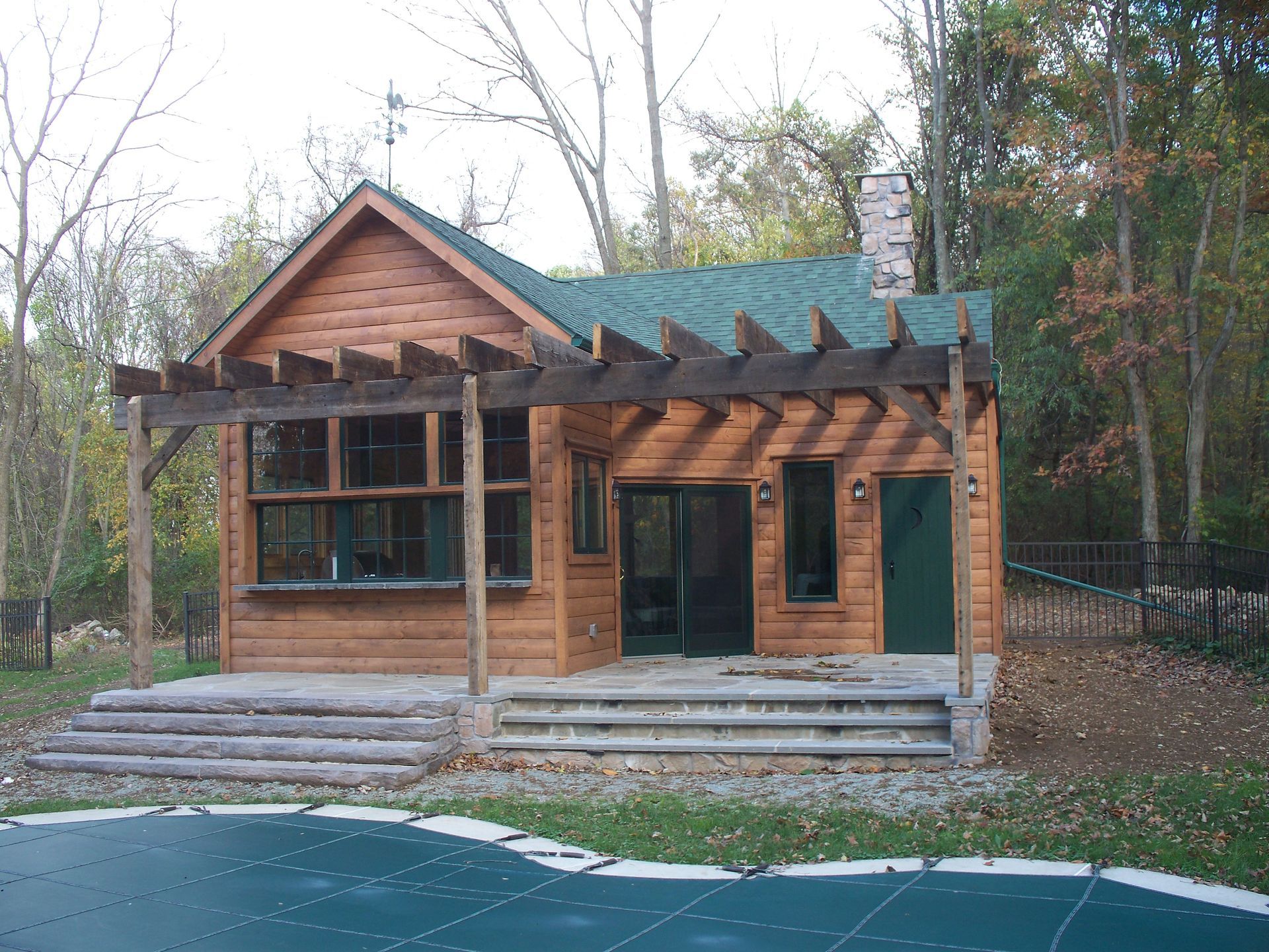 A log cabin with a green roof and a trampoline in front of it