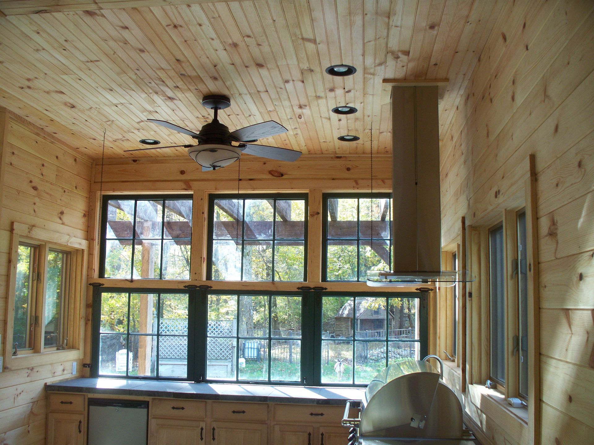 A kitchen with a ceiling fan and lots of windows