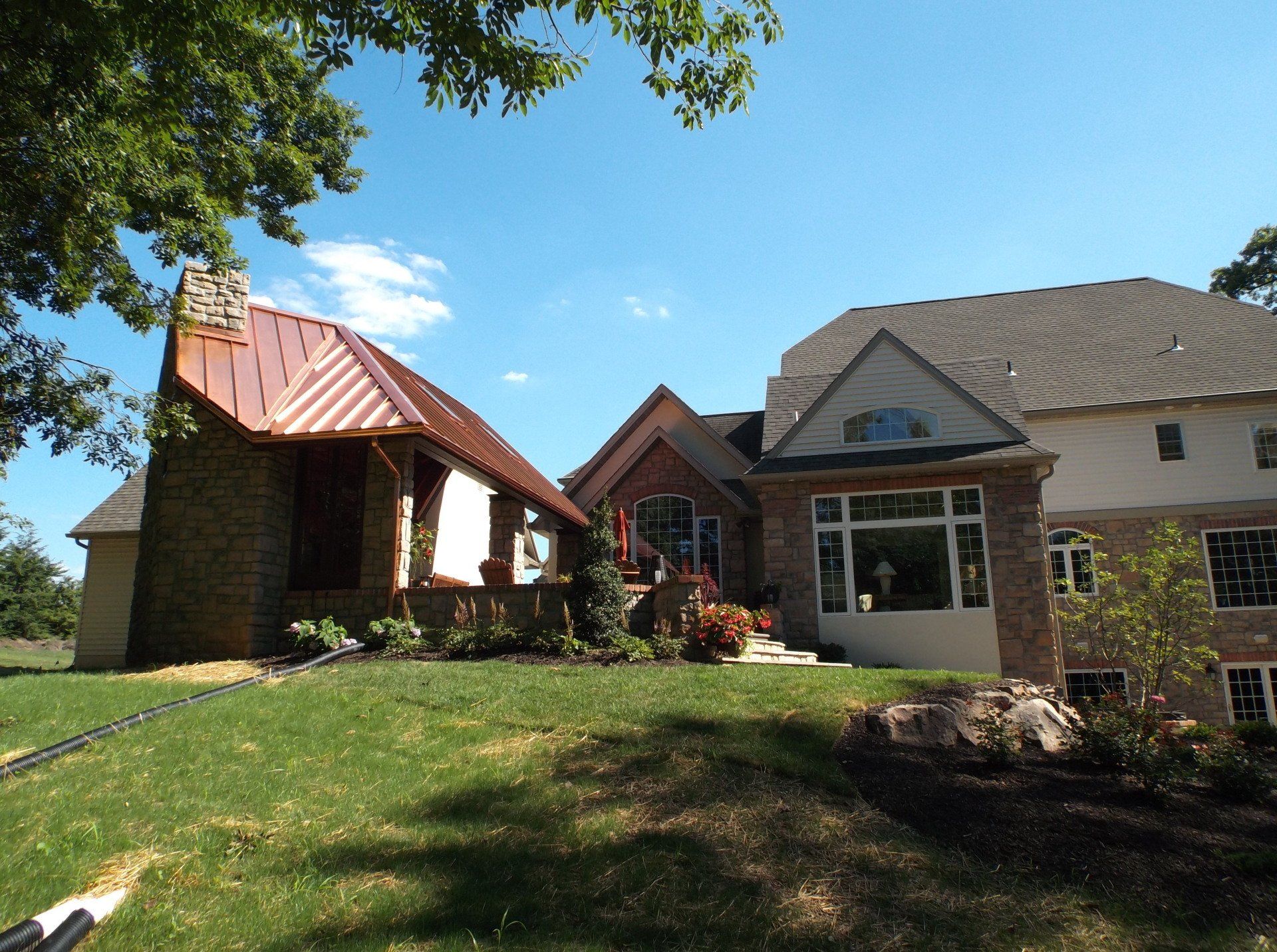 A large house with a copper roof sits on a lush green hillside